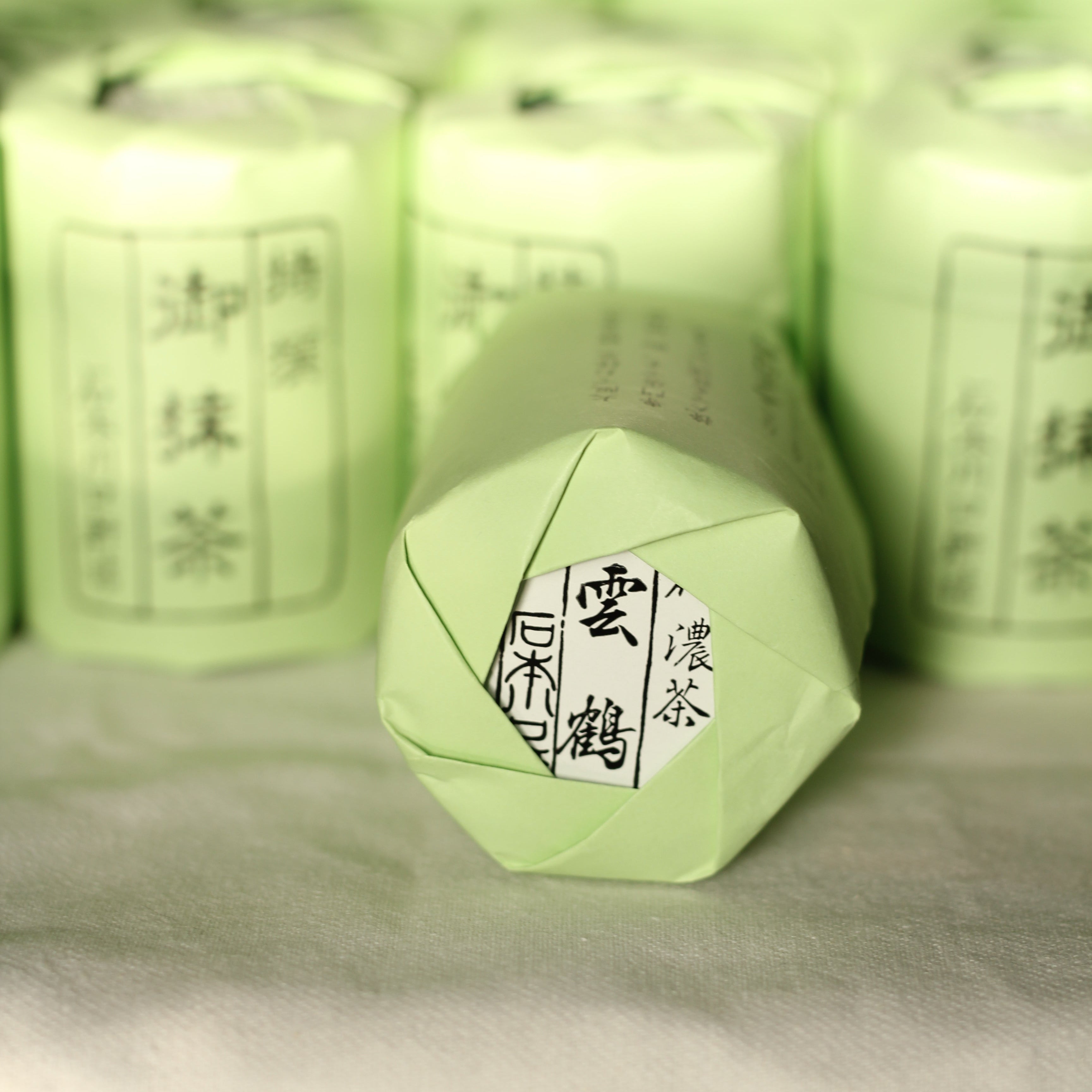 Two cylindrical containers of Ishimoto Kuwaguchi matcha tea, one larger and one smaller, with green labels and Japanese text.