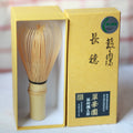 Traditional Japanese tea whisk with a yellow box on a white background