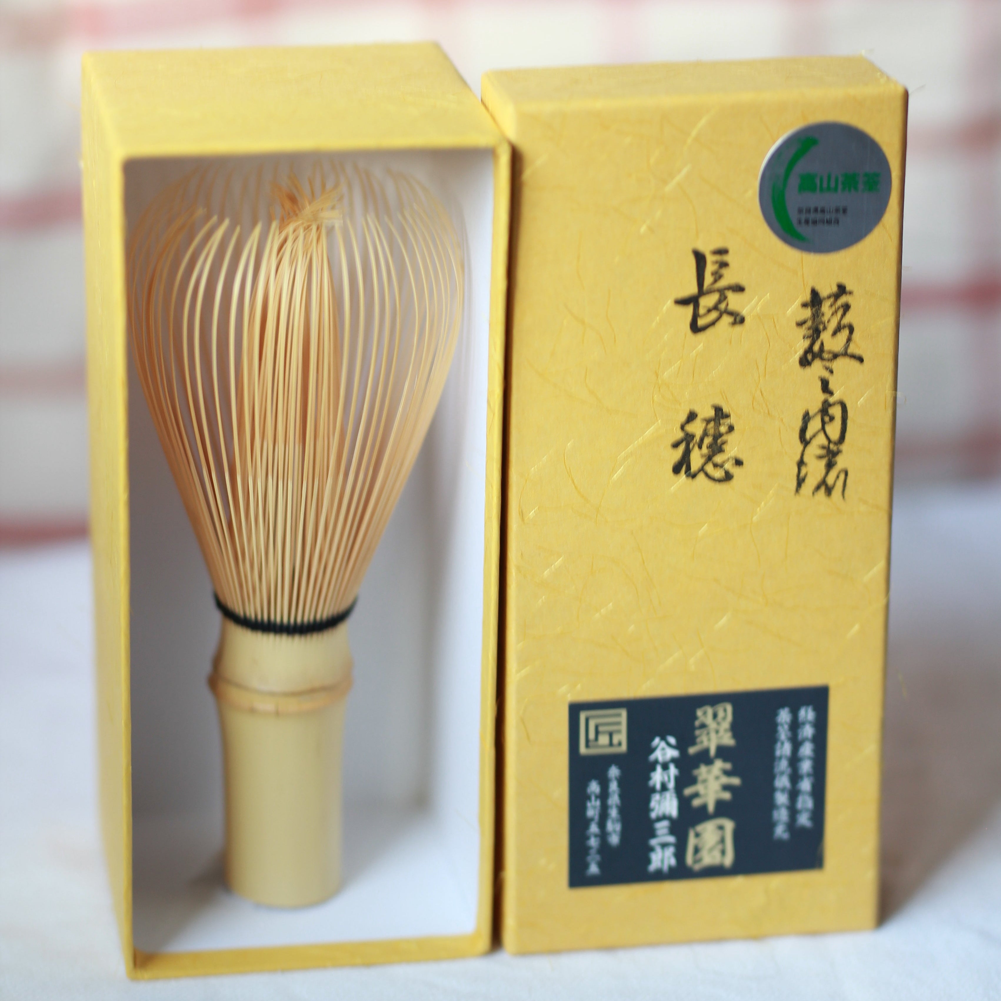 Traditional Japanese tea whisk with a yellow box on a white background